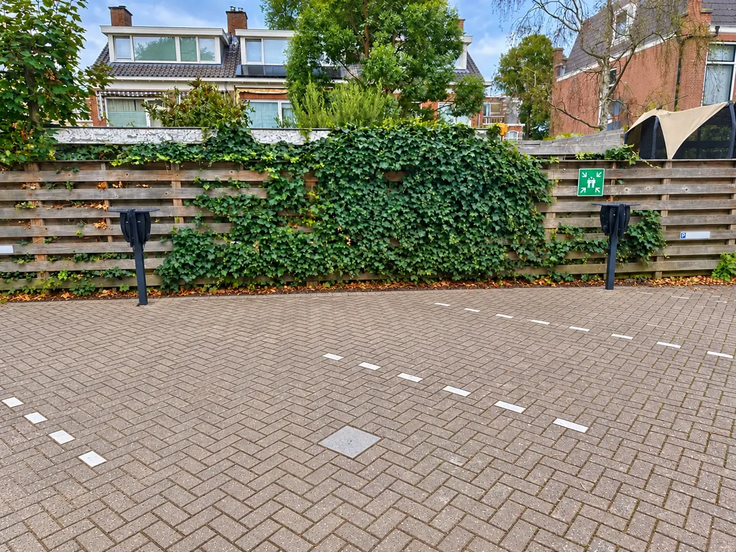 Twee duopalen met laadstations langs de schutting van het parkeerterrein